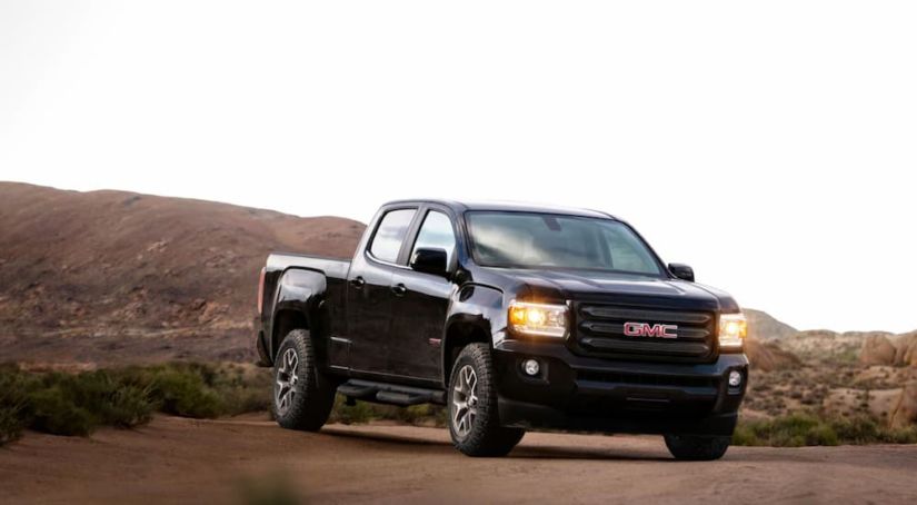 A black 2019 GMC Canyon is parked on dirt.