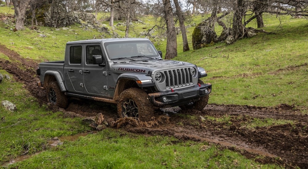 A grey 2020 Gladiator is driving through mud in the woods. 