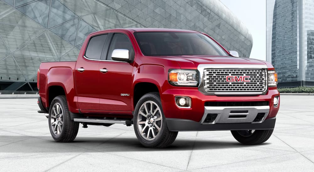 A red 2019 GMC Canyon Denali is parked in front of a glass building.