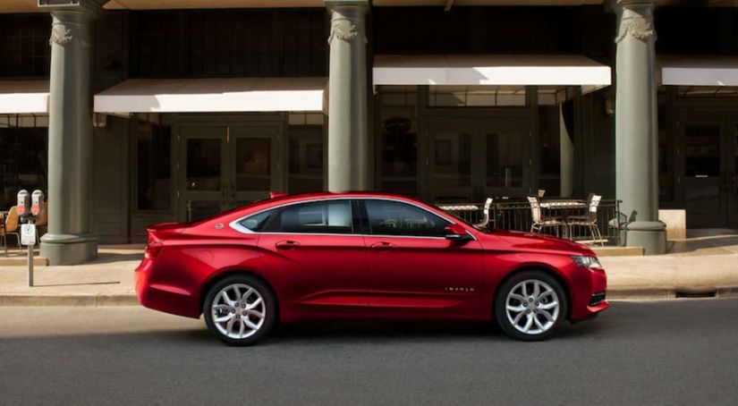 A red 2019 Chevy Impala, an option for Chevy lease deals, is parked in front of a city building.