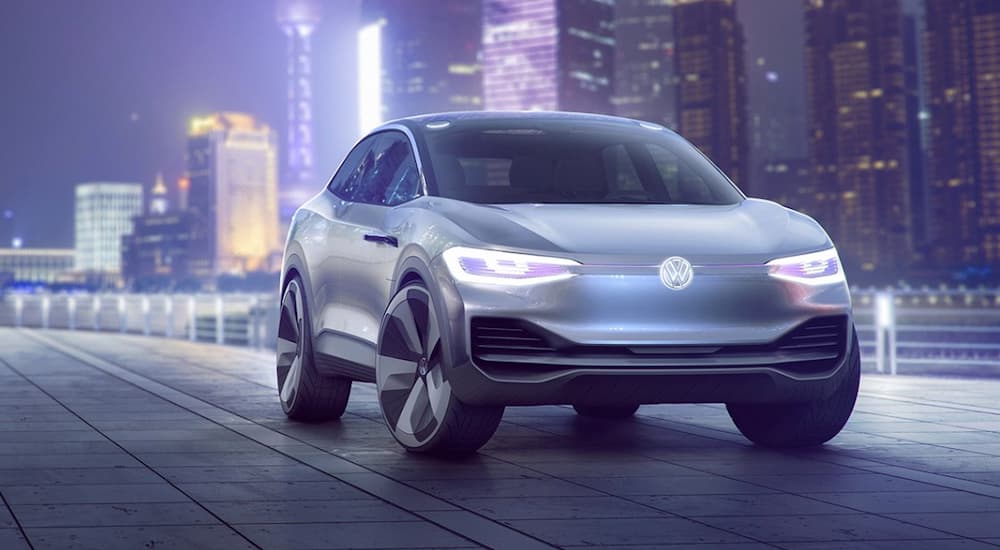 A futuristic silver prototype VW ID. CROZZ is in front of city lights at night.