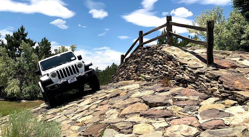 A white 2019 Jeep Wrangler is shown testing the Faricy Boys rock climb at their dealership. 