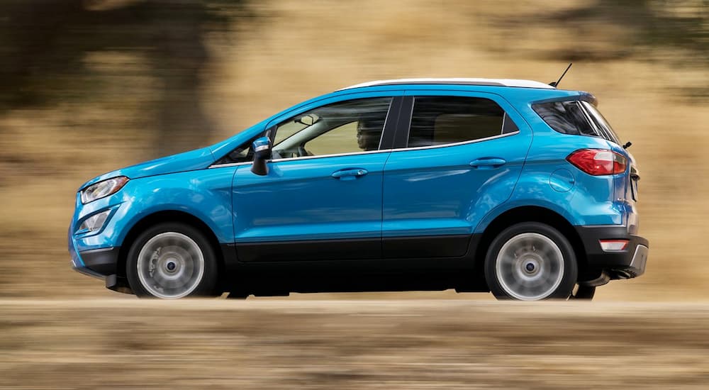 A blue 2019 Ford Ecosport is driving with a blurred background.