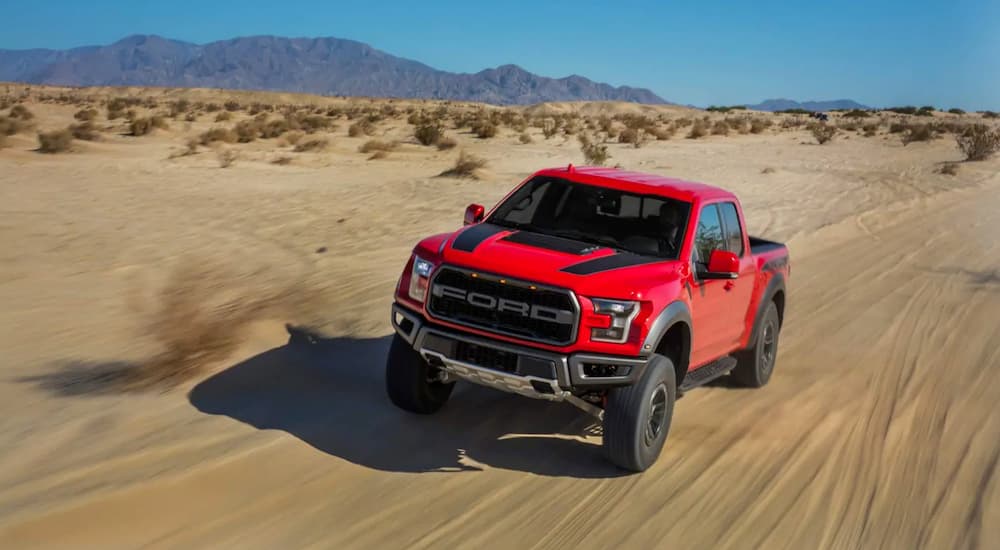 A red 2019 Ford Raptor is driving in the desert.