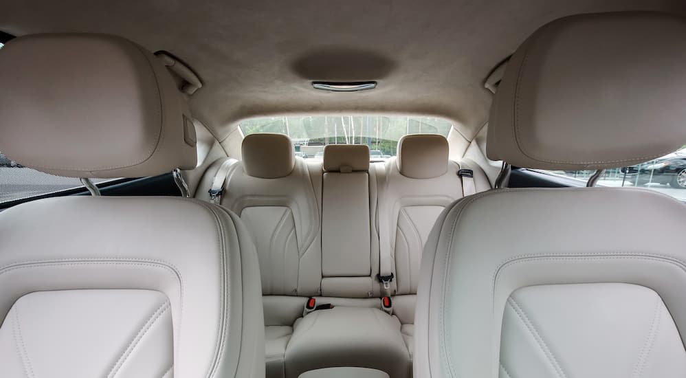 The front and rear seats of a car are shown with white upholstery.
