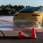 A yellow Porsche is shown on a wet track on one of the top ten test drive tracks.