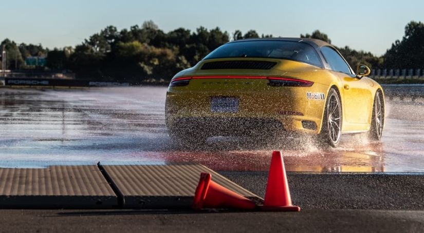 A yellow Porsche is shown on a wet track on one of the top ten test drive tracks.