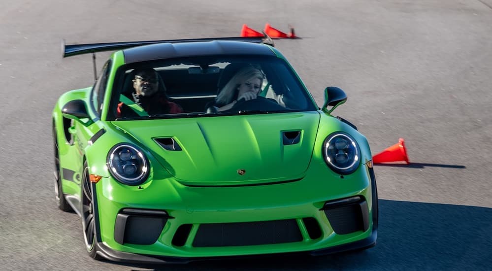 A lime green Porsche 911 is driving around a corner on one of the top ten test drives race tracks in the world. 