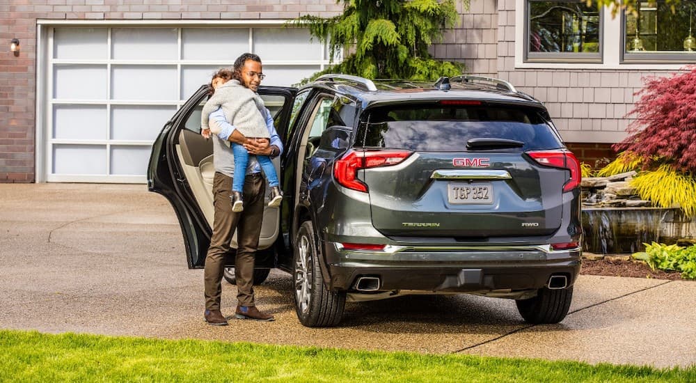 A father is taking his child out of the back of a 2018 GMC Terrain.