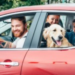 A family and their dog are all in a red car.