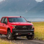 A red 2019 Chevy Silverado 1500 Trailboss is on a dirt path in a field.
