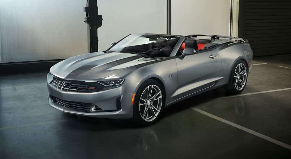 A grey 2019 Chevy Camaro RS Convertible is parked in a garage with the top down. 