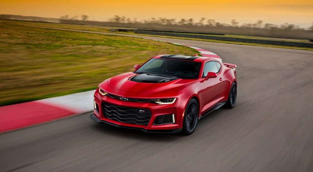 A red 2019 Chevy Camaro is racing around a corner on a race track.