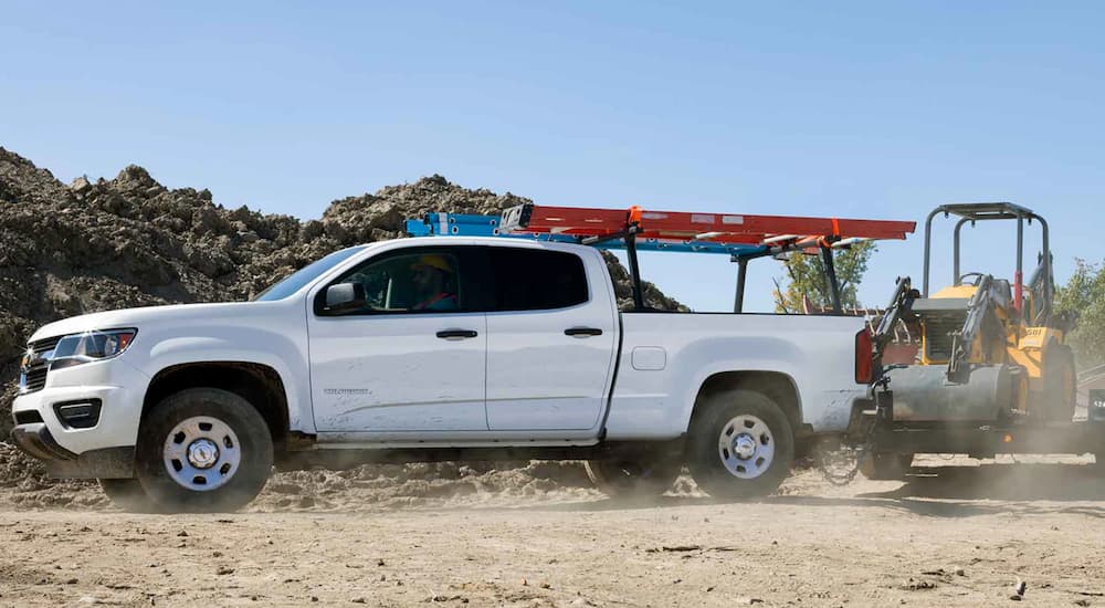 A white 2019 Chevy Colorado work truck is towing equipment.