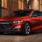A red 2019 Chevy Malibu is parked downtown at night.