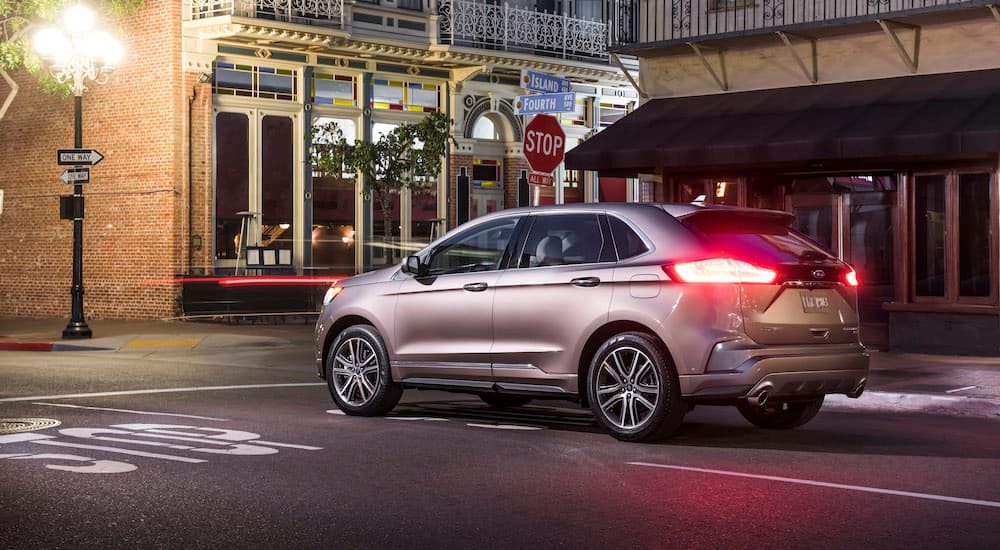 A tan 2019 Ford Edge is at a city intersection at night.