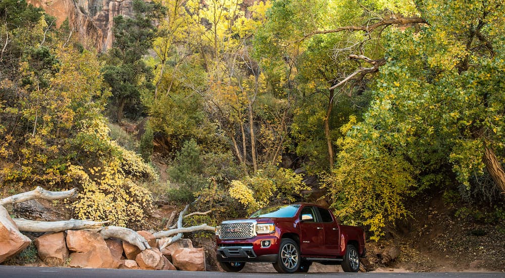 A red 2019 GMC Canyon is next to rocks and a fallen tree.