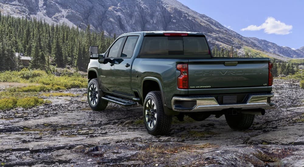 A green 2020 Chevy Silverado 2500HD is on a rocky trail in front of mountains.