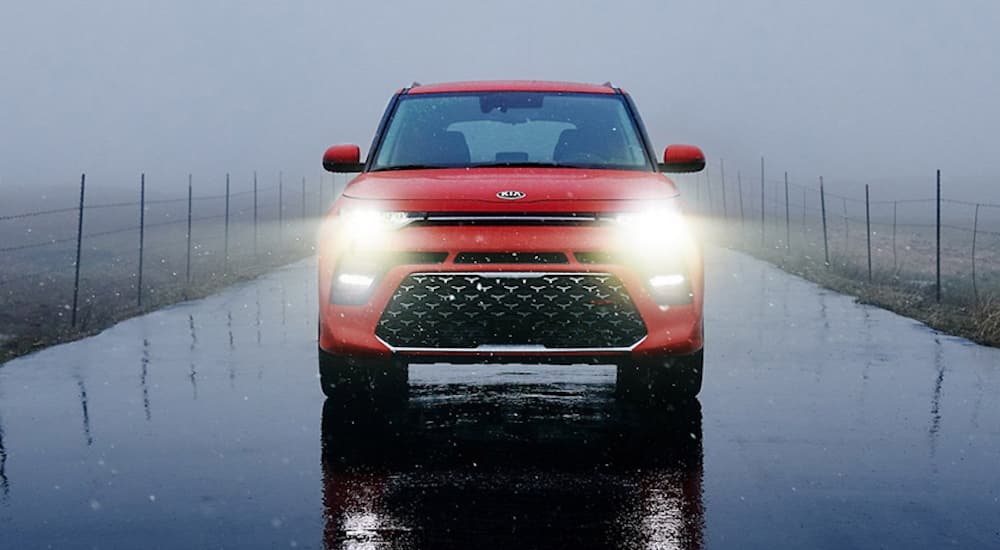 A red 2020 Kia Soul is driving in the rain.