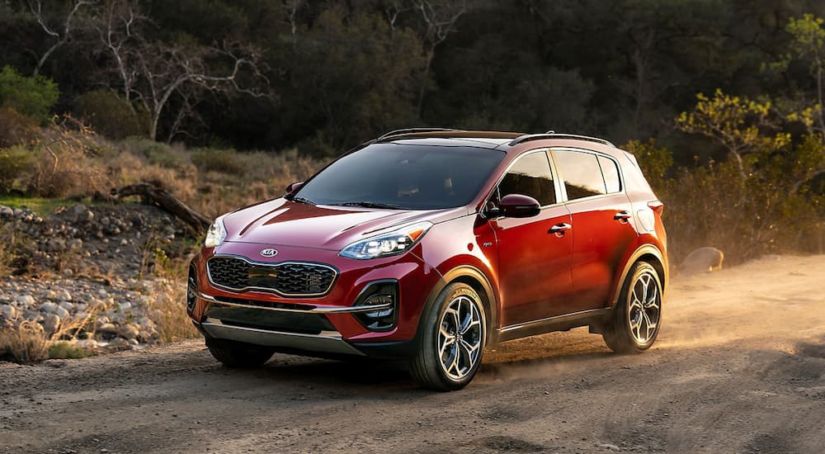 A red 2020 Kia Sportage is parked on a dirt path with dust flying in the air.