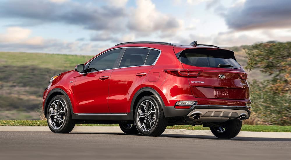 A red 2020 Kia Sportage is parked in a lot with blue sky in the background, 
