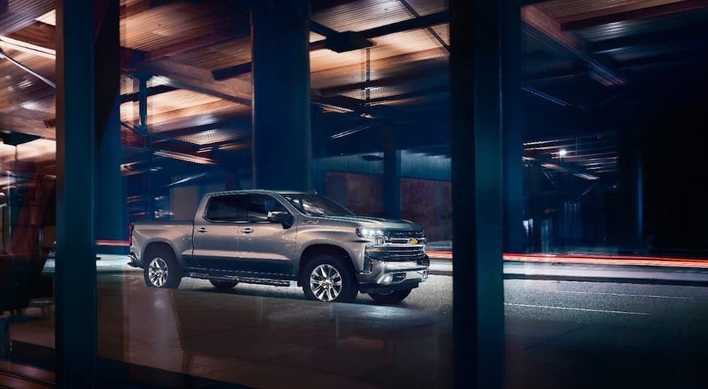 A grey 2019 Chevy Silverado is on the other side of glass windows at night.