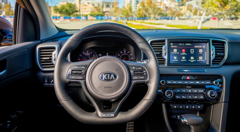 The black interior is shown in the Kia Sportage, focusing on the dashboard.