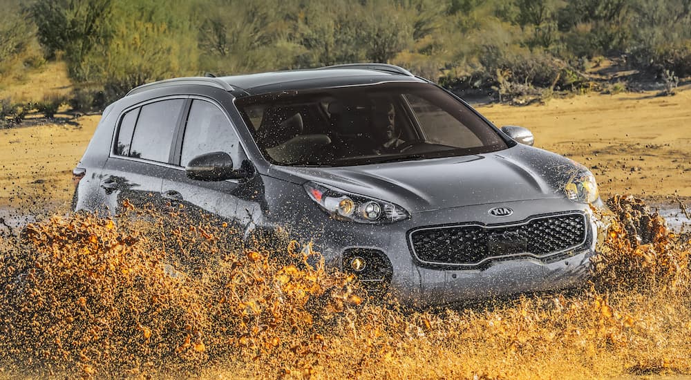 A grey 2019 Kia Sportage, popular among Kia models, is driving through mud.