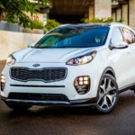 A white 2019 Kia Sportage is on a city side street.
