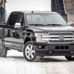 A black 2018 Ford F-150 is parked on a snowy town road.