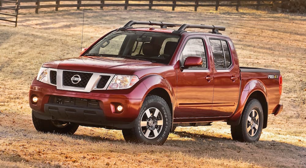 A red 2009 Nissan Frontier is in a sunny field.