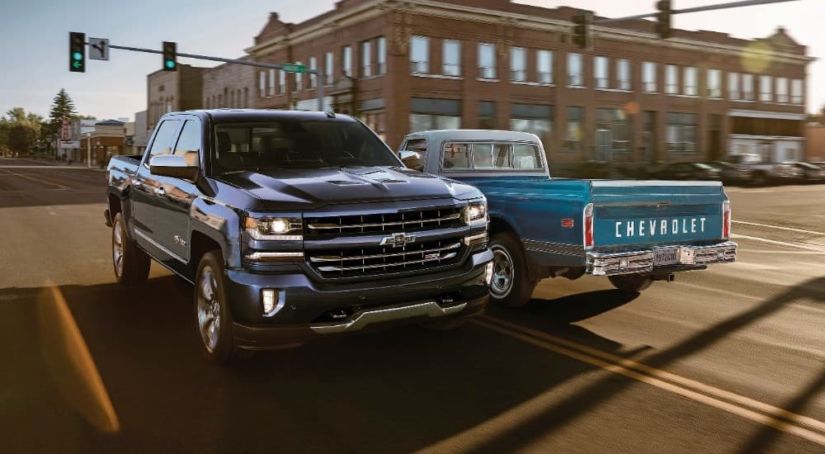 A blue 2018 Chevy Centennial Edition Silverado is driving past a blue 1972 C10 in an intersection.