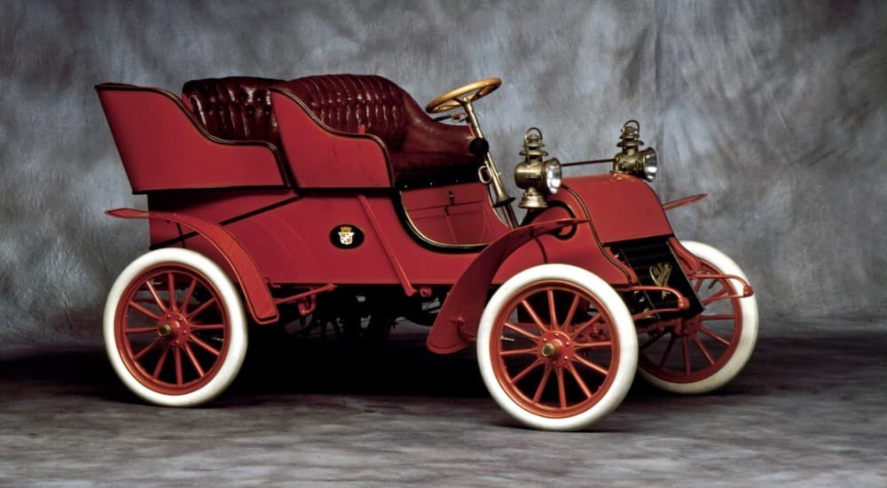 A red 1903 Cadillac ModelA Runabout is in front of a grey background.