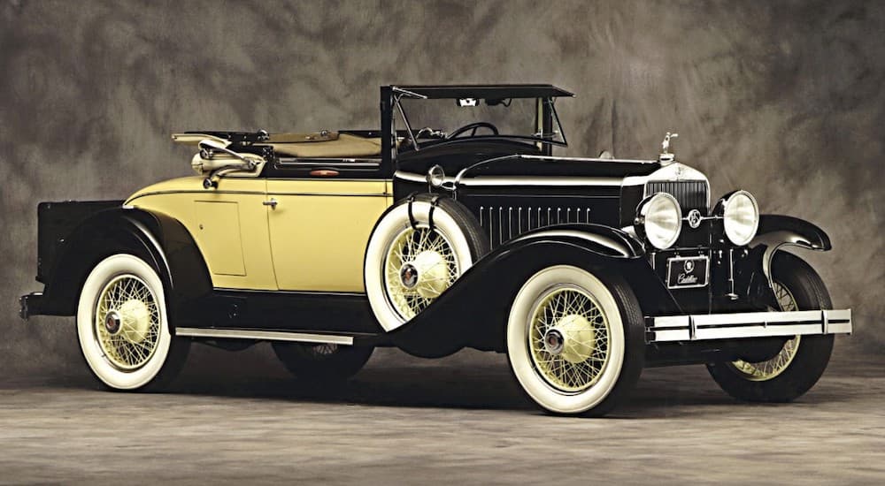 A yellow 1927 Cadillac LaSalle, which would be hard to find as a used luxury car today, is in front of a grey background.