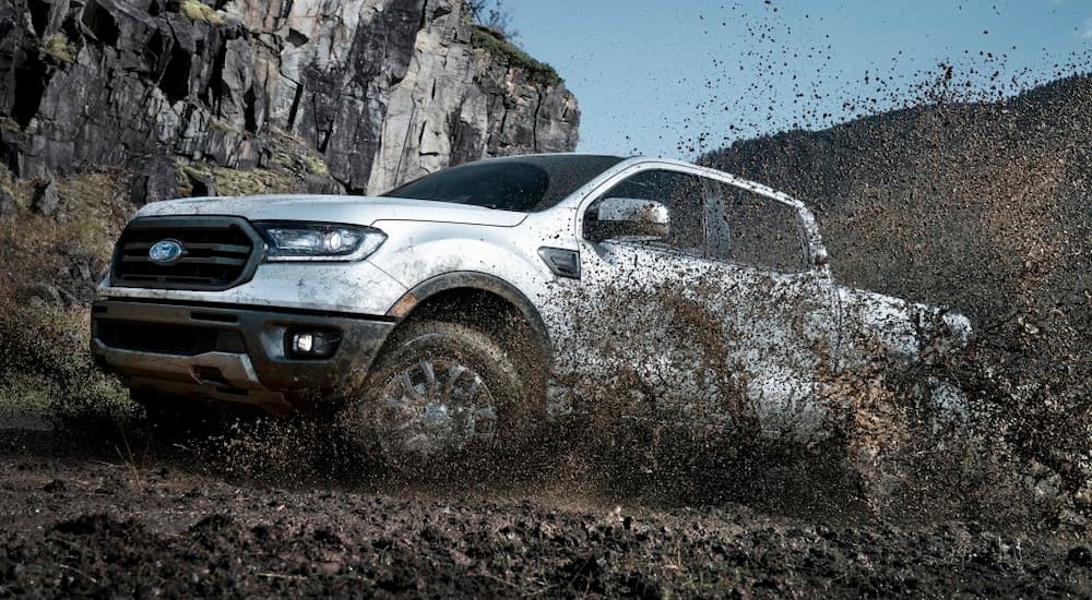 A white 2019 Ford Ranger is in the mud.