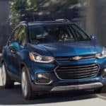 A blue 2020 Chevy Trax is driving on a city highway.