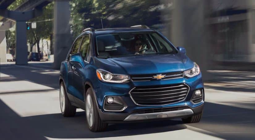A blue 2020 Chevy Trax is driving on a city highway.