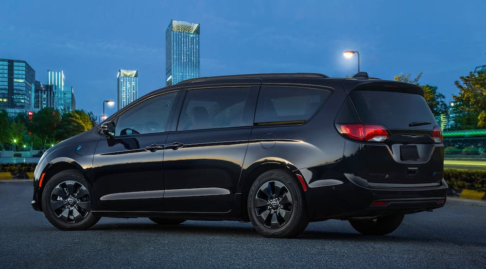 A black 2020 Chrysler Pacifica is parked with a night time city skyline in the background. 