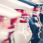 Car trunks in a car lot are shown in close up.