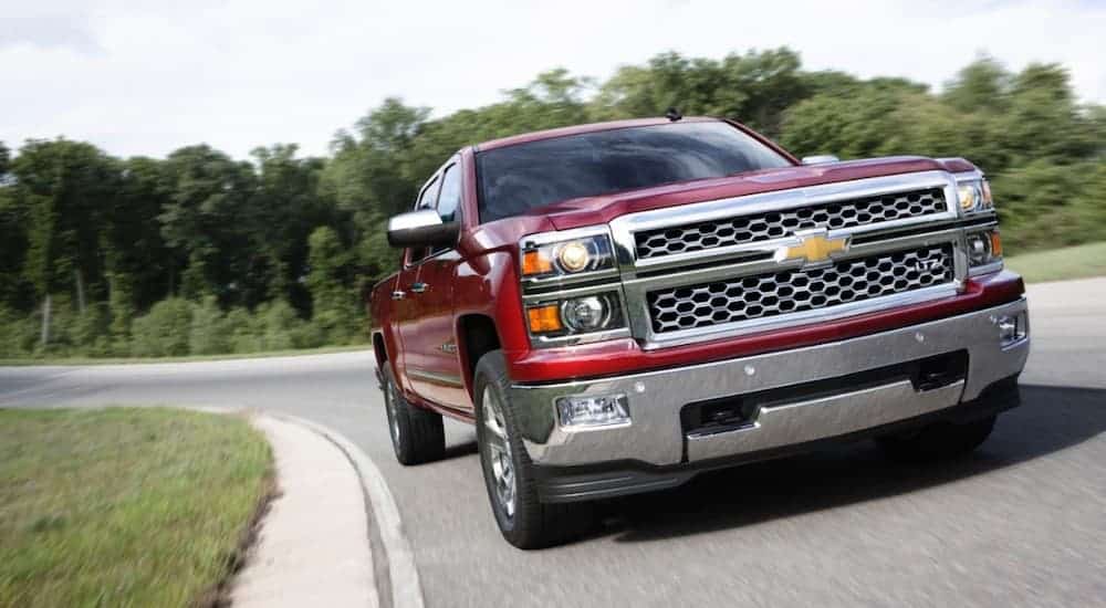 A red 2014 Chevy Silverado is shown from the front driving around a corner.