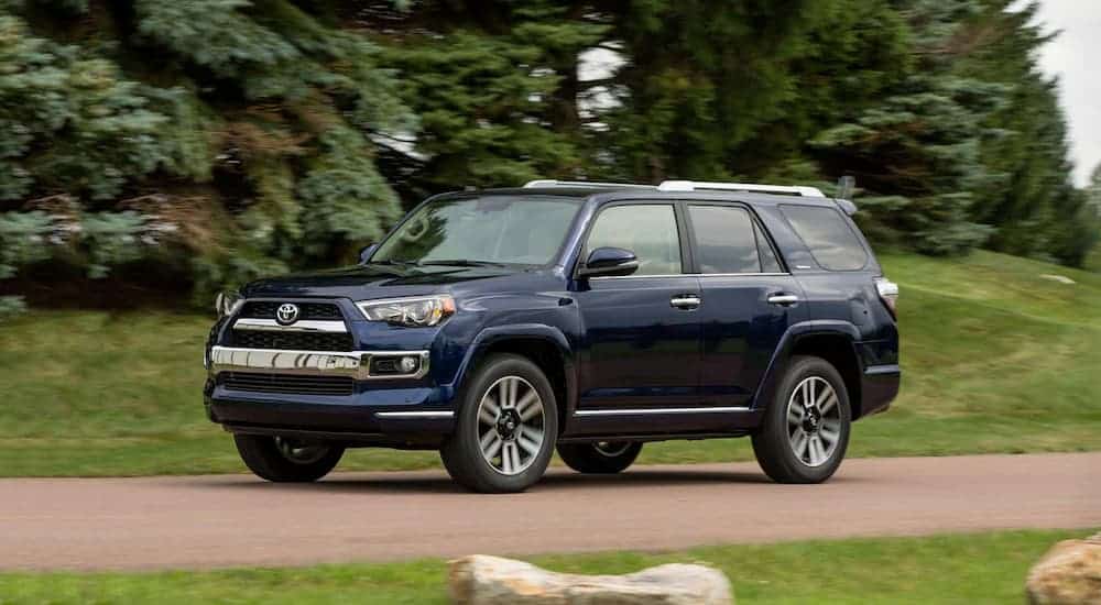 A blue 2018 Toyota 4Runner is on a tree-lined road.
