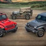 Two 2018 Jeep Wranglers are in front of an antique military Jeep.