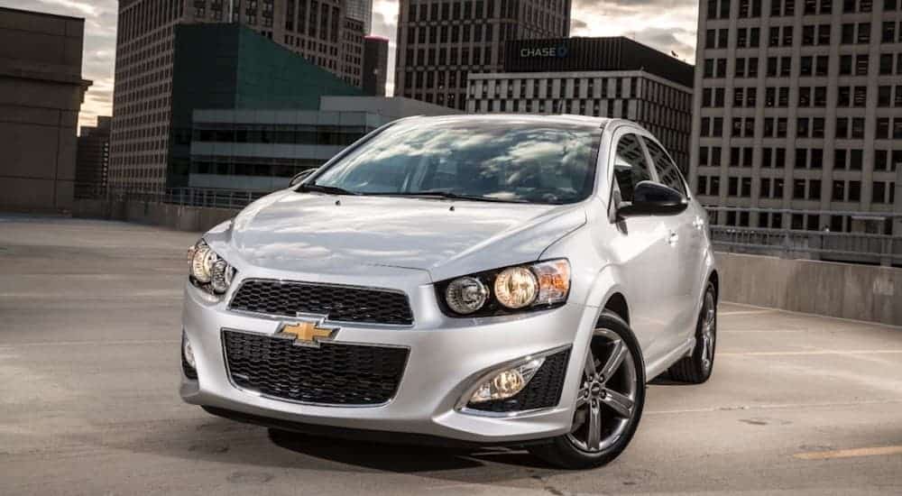 A silver 2014 Chevy Sonic, popular among affordable, quality cars at buy here pay here dealerships, is parked on a rooftop parking garage.