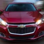 The front of a red 2015 Chevy Malibu is shown with a blurry background.