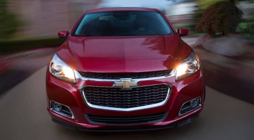 The front of a red 2015 Chevy Malibu is shown with a blurry background.