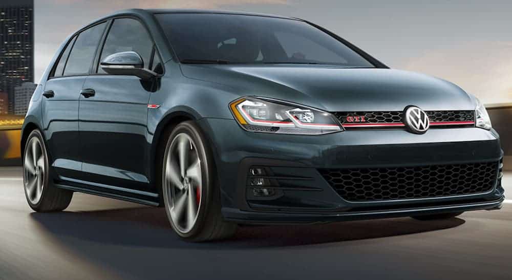 A black 2019 Volkswagen Golf GTI, popular in current auto news, is driving on a highway.