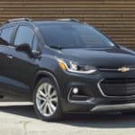 A black 2020 Chevy Trax is parked in front of a wooden wall.
