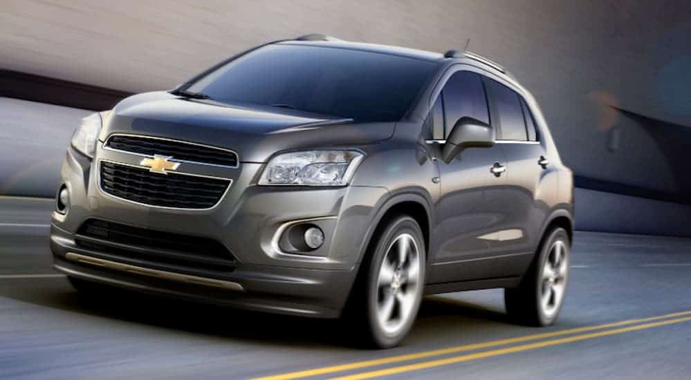 A grey 2013 Chevy Trax is driving on a highway. 
