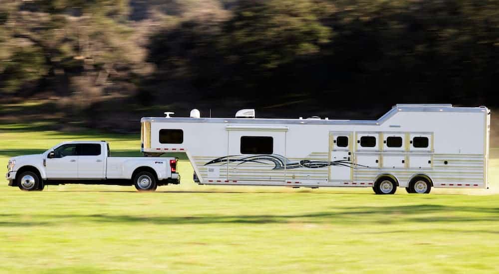 A white 2020 Ford Super Duty is towing a 20 foot RV trailer. 