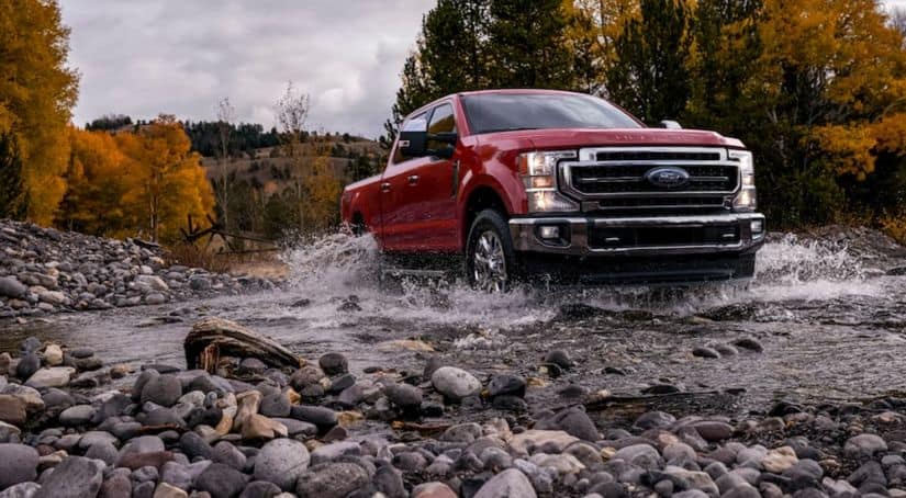 A red 2020 Ford Super Duty is driving through a rocky water way.